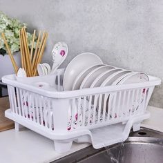 a white dish rack filled with dishes on top of a kitchen counter next to a sink