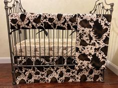 a black and white cow print crib bedding in a room with hardwood floors