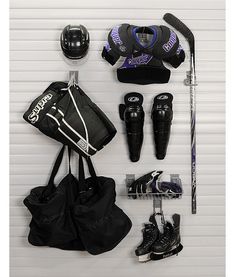 an assortment of sports equipment is displayed on a white wall with roller skates and helmet