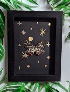 a black frame with gold stars and a butterfly in it