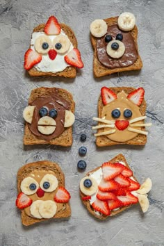 four slices of toast with fruit and chocolate on them, each decorated like a cat