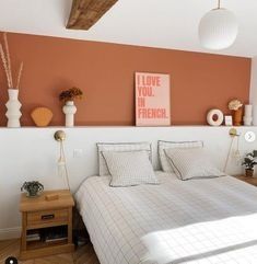 a bed sitting in a bedroom next to a wooden table and white walls with pictures on the wall