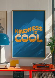 a blue poster with the words kindness is cool on it next to a record player