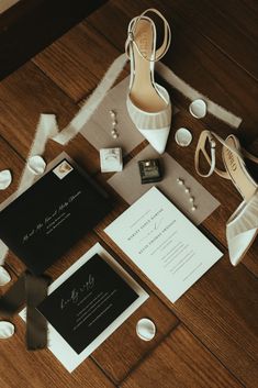 the wedding stationery is laid out on the floor with shoes, rings and jewelry