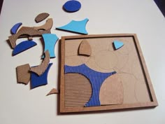 some cut out pieces of paper sitting on top of a white table with blue and brown shapes