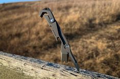 a pair of scissors sitting on top of a wooden fence in front of a field