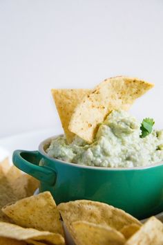 a green bowl filled with guacamole and tortilla chips