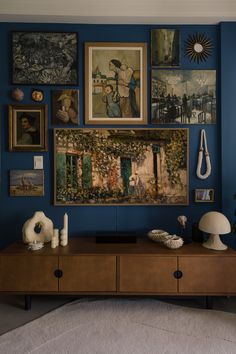 a living room with blue walls and pictures on the wall, including an art piece