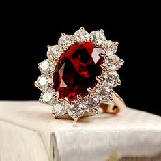 a red and white diamond ring sitting on top of a book