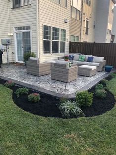 a patio with couches and chairs in the grass