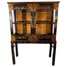 an old black and gold painted cabinet with glass doors on one side, two drawers on the other