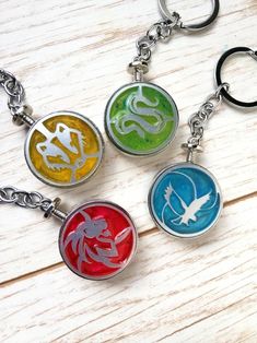 four different colored key chains with an image of a bird on one side and a dragon on the other