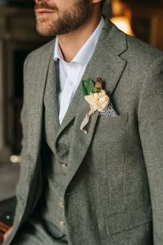 a man in a gray suit with a flower on his lapel