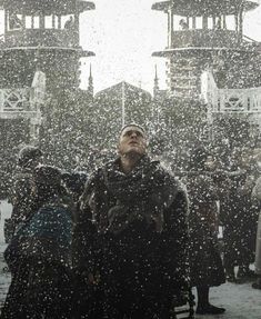 a man standing in the snow with his eyes closed and people looking up at him