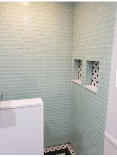 a white toilet sitting inside of a bathroom next to a sink and shower head mounted on a wall