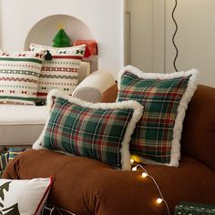 a living room filled with lots of pillows and christmas lights on the couches next to each other