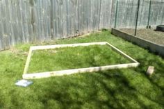 a yard with grass and a fence in the background, including a raised garden bed