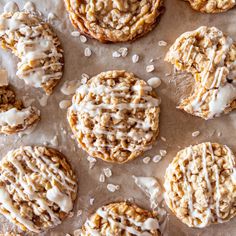 several cookies with white icing and sprinkles on a piece of parchment paper