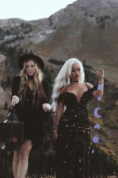 two women dressed in black are walking down the hill with one holding a bag and another carrying a purse