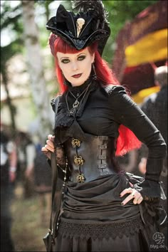 a woman with red hair wearing a black corset and matching hat is posing for the camera