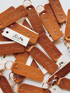 leather name tags are laid out on top of each other, with key chains attached to them