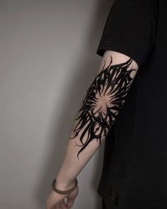 a man's arm with black ink on it and an abstract design in the middle