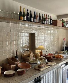 a kitchen counter filled with lots of food and wine bottles on top of the shelves