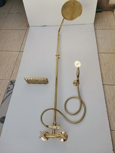 a gold shower faucet sitting on top of a tile floor next to a wall