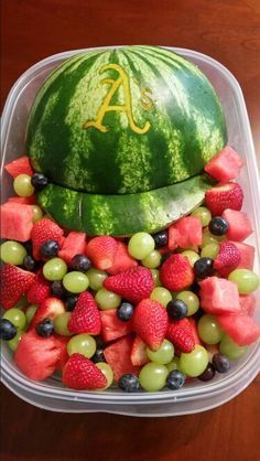 a plastic container filled with watermelon, grapes and strawberries