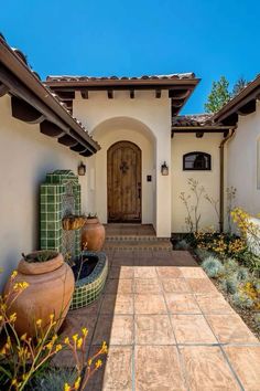 the front entrance to a home with flowers and potted plants