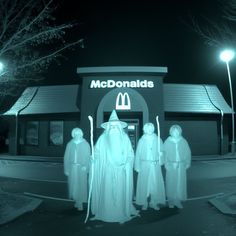 three people dressed up as ghostes in front of mcdonald's restaurant at night