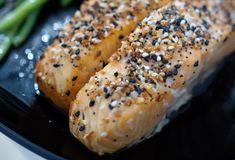 sesame seed crusted salmon and asparagus on a black plate