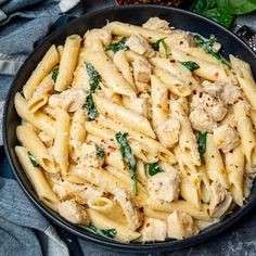 pasta with chicken, spinach and sauce in a skillet on a blue towel