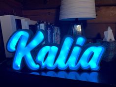 the word kalla is lit up with blue lights in front of a lamp and bookshelf