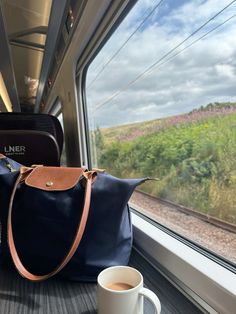 a blue purse sitting on top of a train next to a cup of coffee