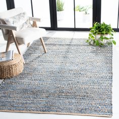 a living room area with a chair, rug and potted plant