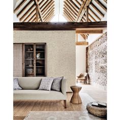 a living room filled with furniture next to a brick wall and wooden beams on the ceiling