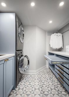 a washer and dryer are in the middle of a room with blue cabinets