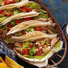 three tacos with chicken, tomatoes and lettuce are on a white plate