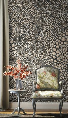 a chair and table in front of a wallpapered room with flowers on it