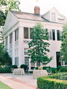 a large white house sitting on top of a lush green field