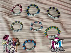 six bracelets with different designs on them sitting on top of a white bed sheet