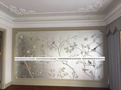 a wall with birds and flowers on it in a room that has wood flooring