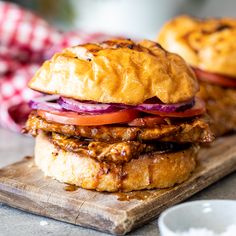 two chicken burgers sitting on top of a wooden cutting board