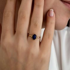 a close up of a person wearing a ring with a blue stone on it's finger