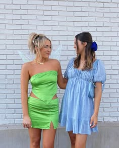 two women dressed in fairy costumes standing next to each other, one holding the hand of another woman