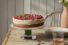 a cake sitting on top of a wooden table next to a vase filled with flowers