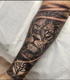 a man's arm with a lion and tree tattoo on the left side of his arm