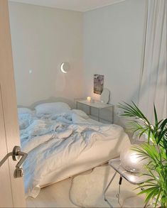 a bedroom with a bed, night stand and potted plant