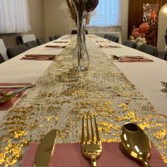 the table is set with silverware and pink napkins, along with gold - plated utensils